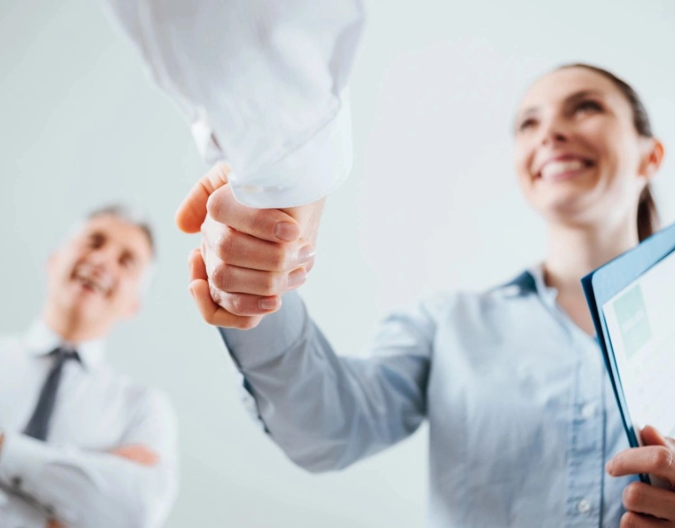 Two people shaking hands in a room.