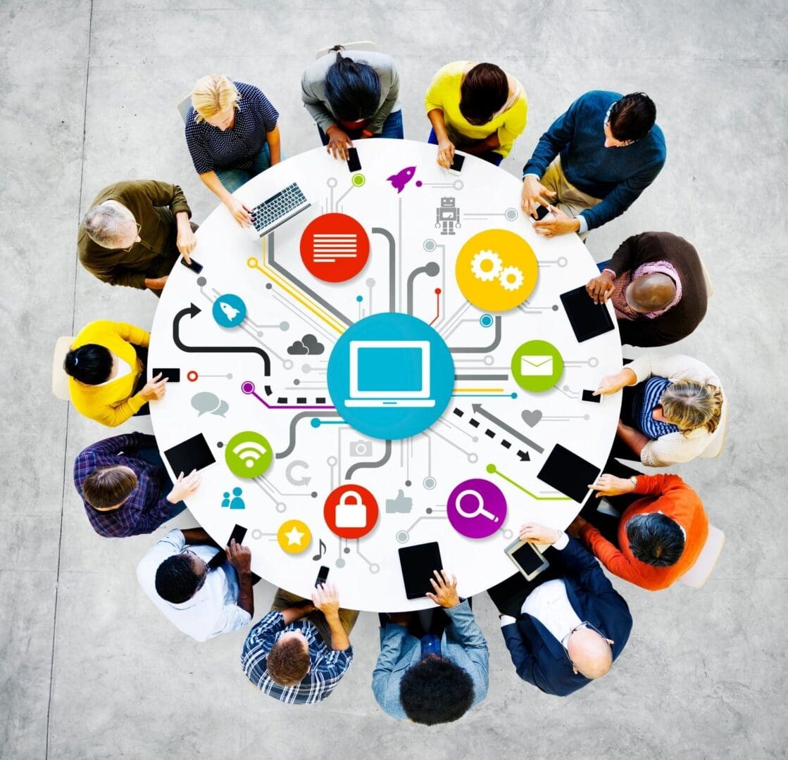 A group of people sitting around a table with computers on it.